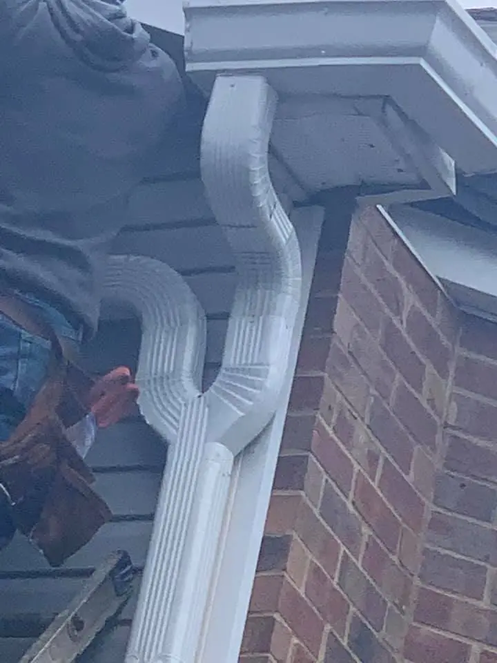 Installing a new white downspout and gutter on a brick home