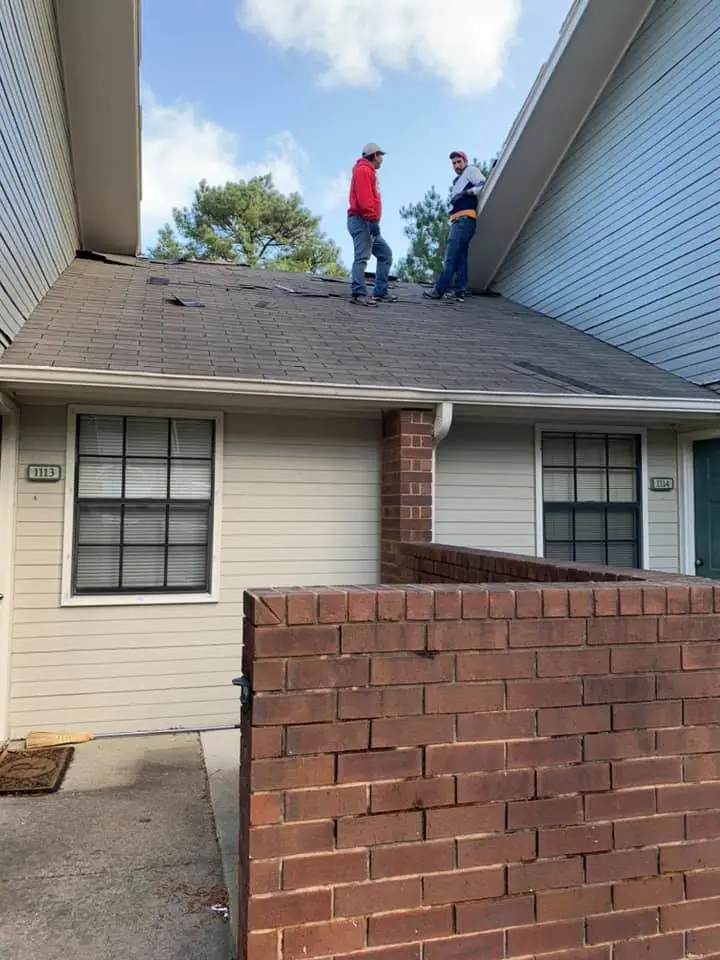 Two roofers on a townhome roof between units
