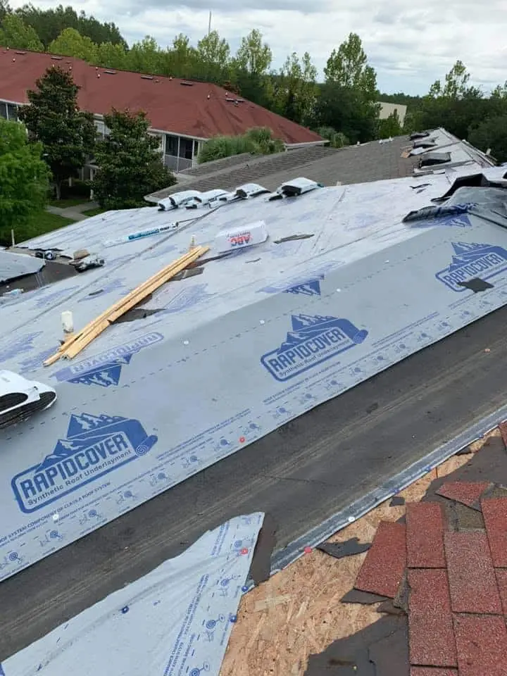 Synthetic underlayment going down on a roof deck before new shingles